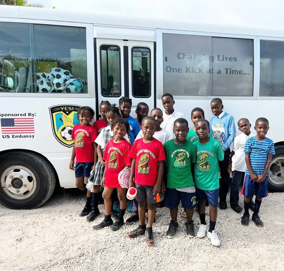 A group of children standing in front of a bus.
